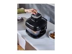 A person's hand adjusting the settings on a black air fryer with potato wedges inside.