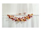 Autumn garland with leaves, pumpkins, and pinecones on a white wainscoting shelf.