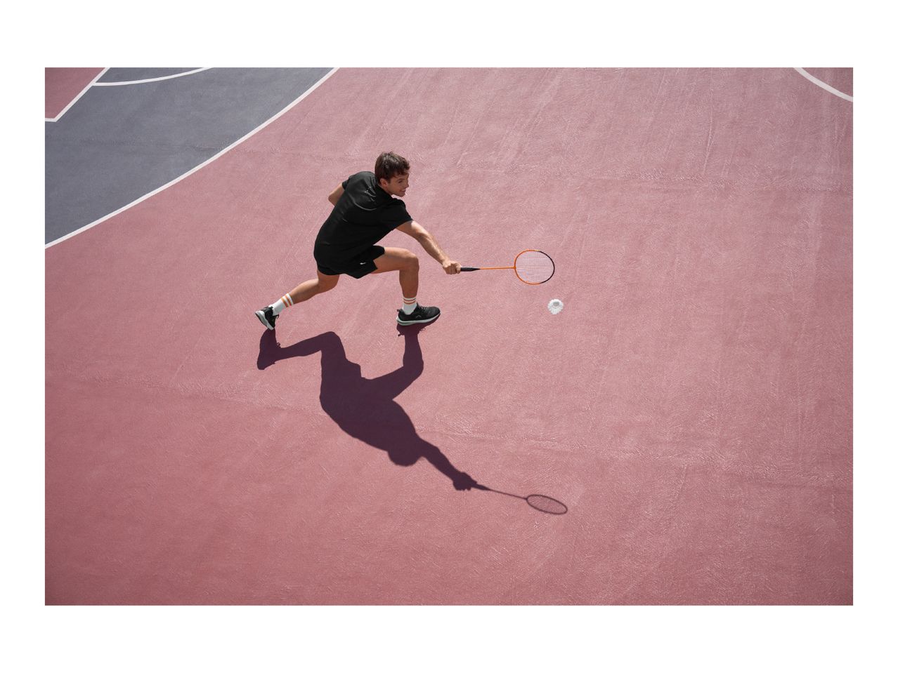 Man playing badminton on a court, hitting a shuttlecock with a racket.