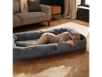 A woman sleeping in a large grey Silentnight Human Pet Bed on a wooden floor.