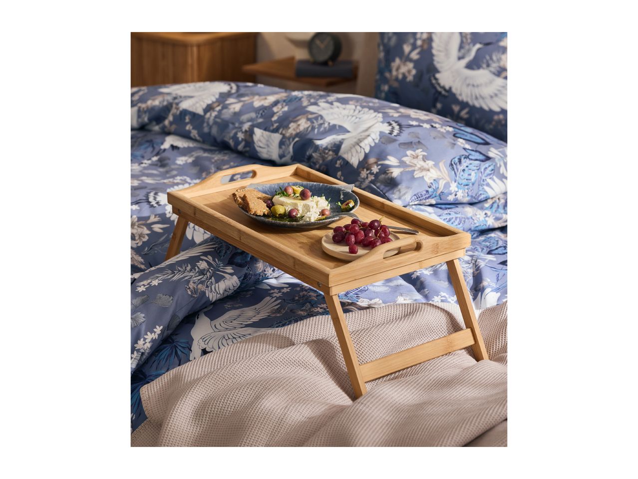 Breakfast in bed with a blue floral duvet cover and a wooden bed tray.