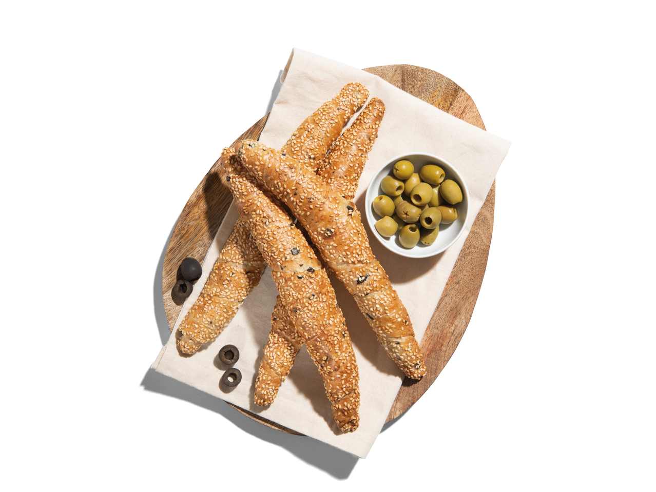 Szezámmagos grissini olajbogyókkal fa táblán.
