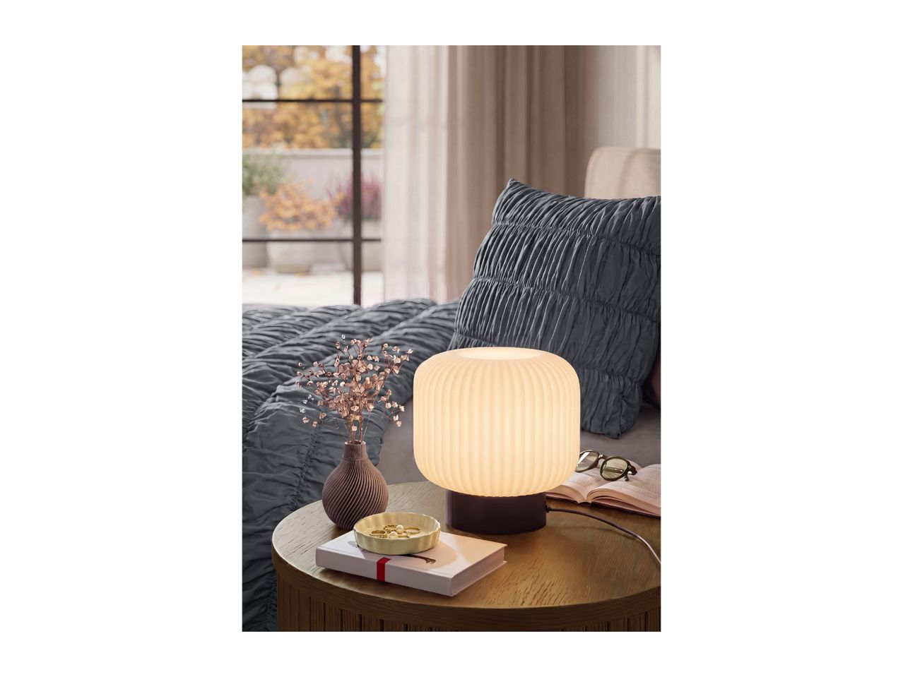 Cozy bedroom scene featuring a glowing table lamp on a wooden nightstand.