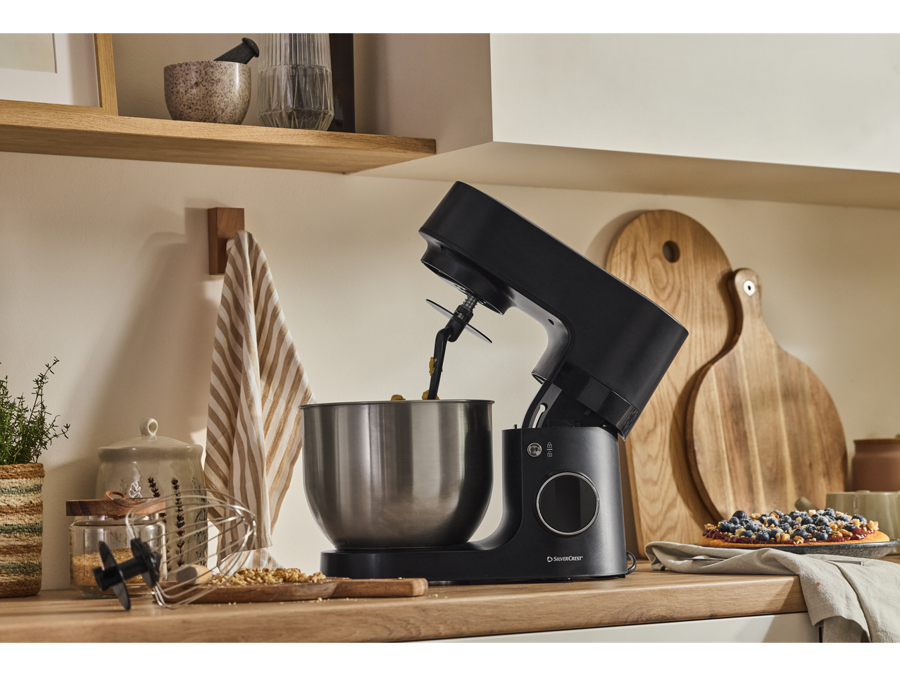 A black SilverCrest stand mixer with a stainless steel bowl on a kitchen counter.