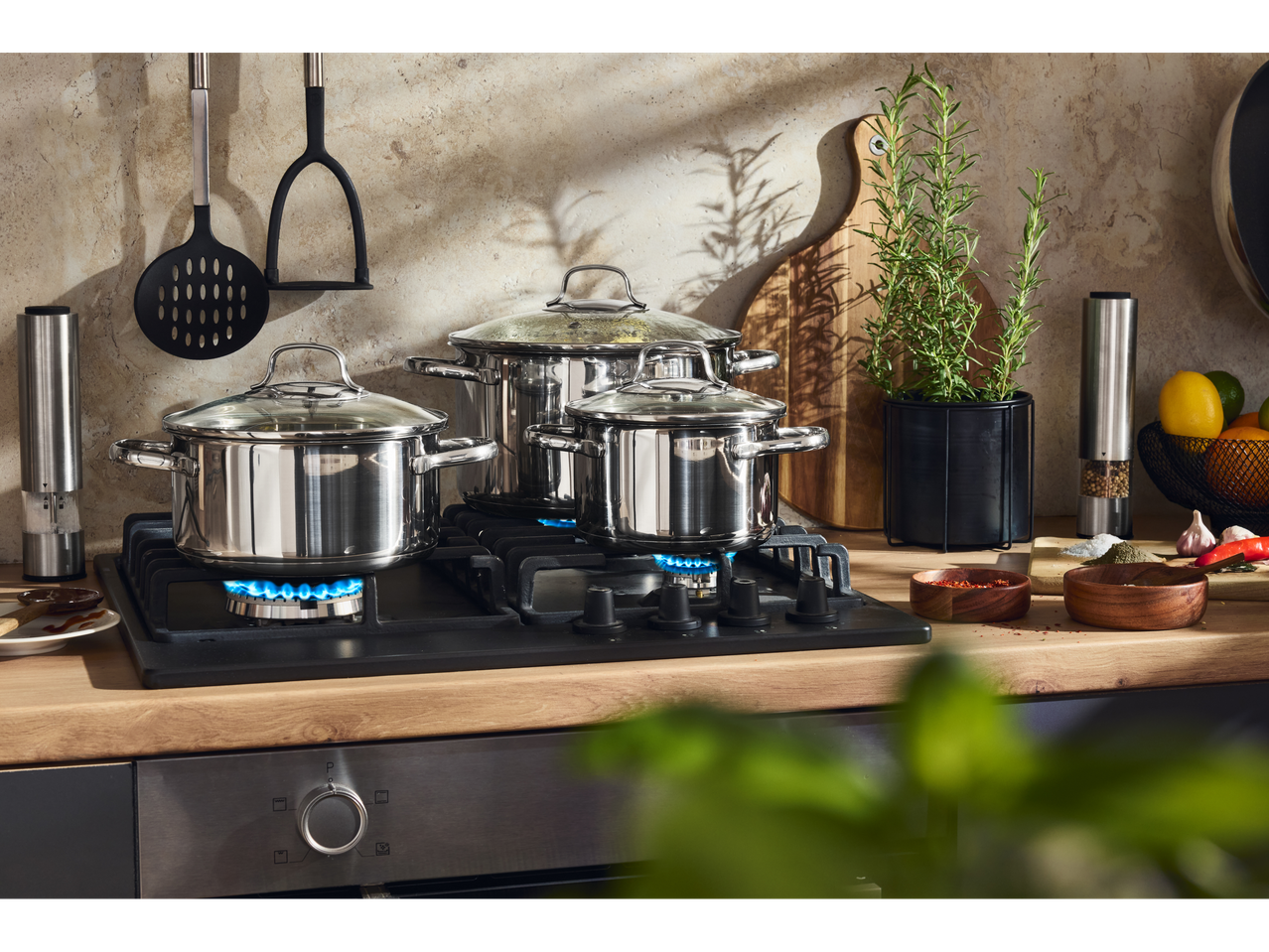 Oale din oțel inoxidabil pe aragaz cu ierburi proaspete și condimente într-o bucătărie.