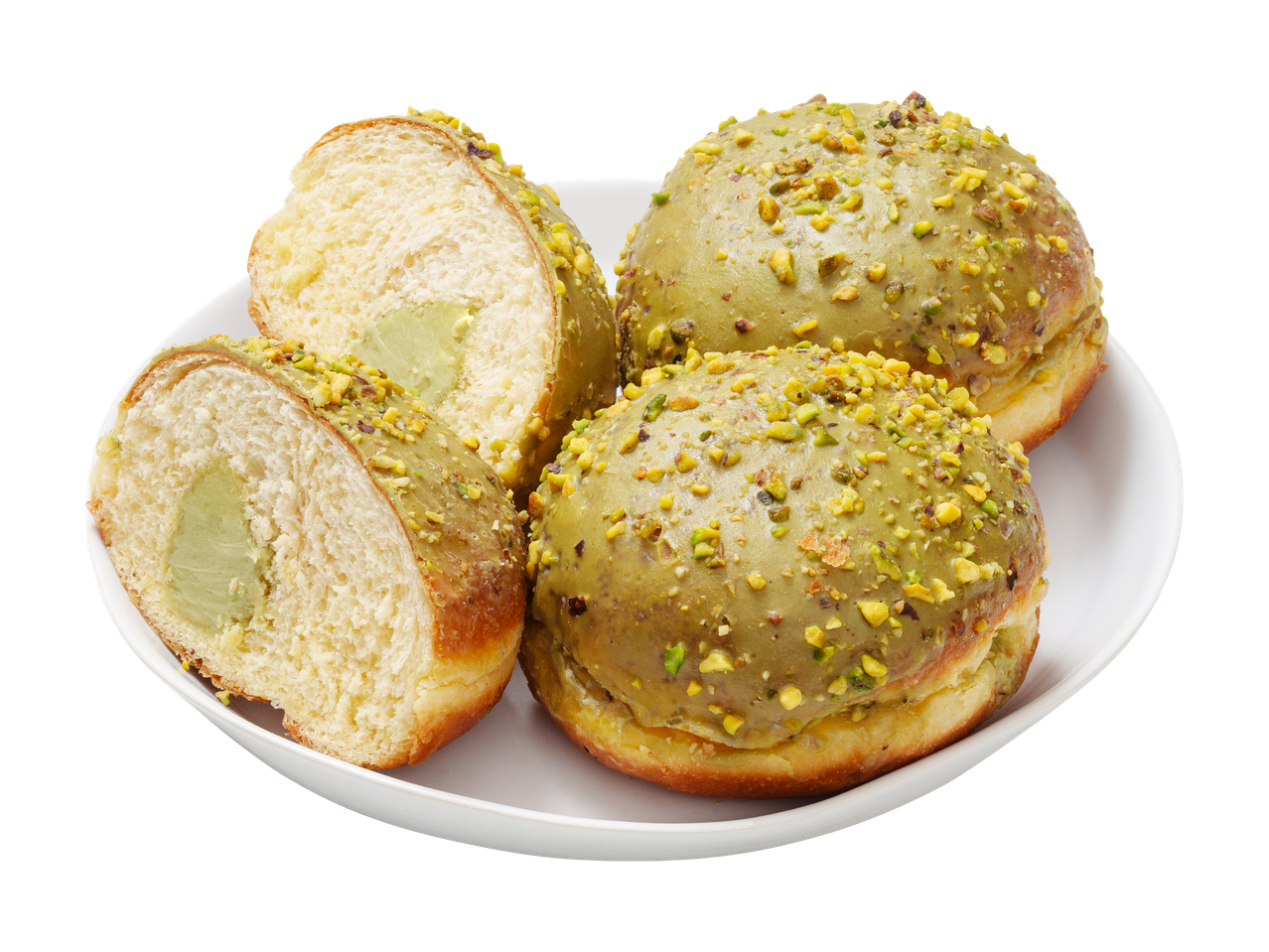 Pistaasitäytteisiä munkkeja valkoisella lautasella, yksi leikattu kahtia.