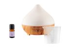 White ceramic essential oil diffuser with wooden base, accompanied by a small bottle of oil and a measuring cup.