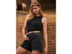 Žena u crnoj majici bez rukava i farmerkama pored bala sena.