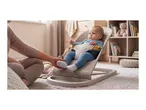 Baby in a bouncer, with an adult's hand touching the baby's foot.