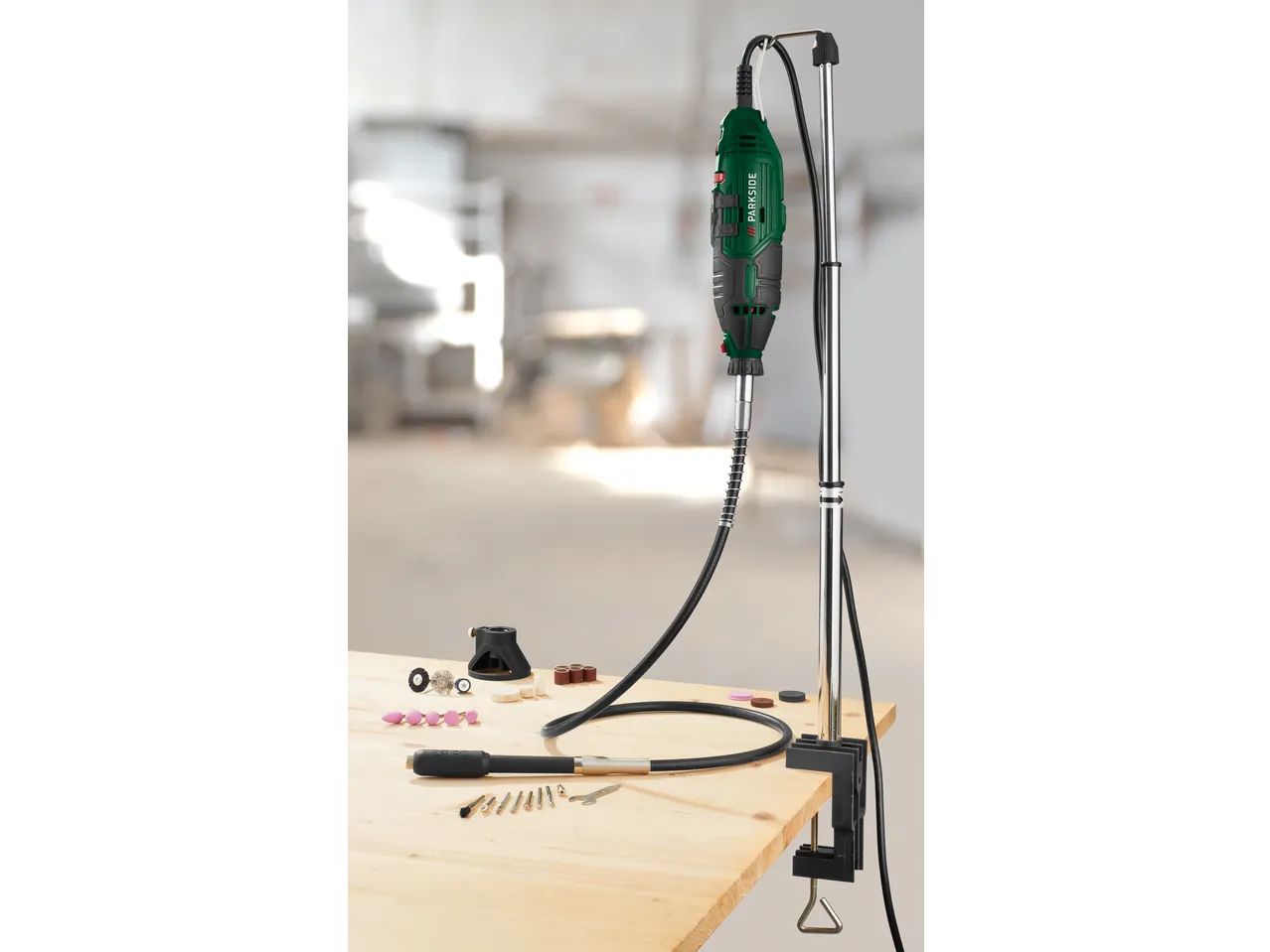 Rotary tool with flexible shaft and various accessories on a wooden workbench.
