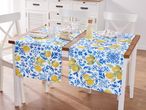 Dining table with two blue and yellow lemon-patterned table runners, set with plates, glasses, and snacks.