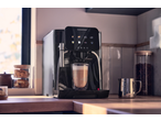 Automatic coffee machine brewing a latte in a kitchen setting.