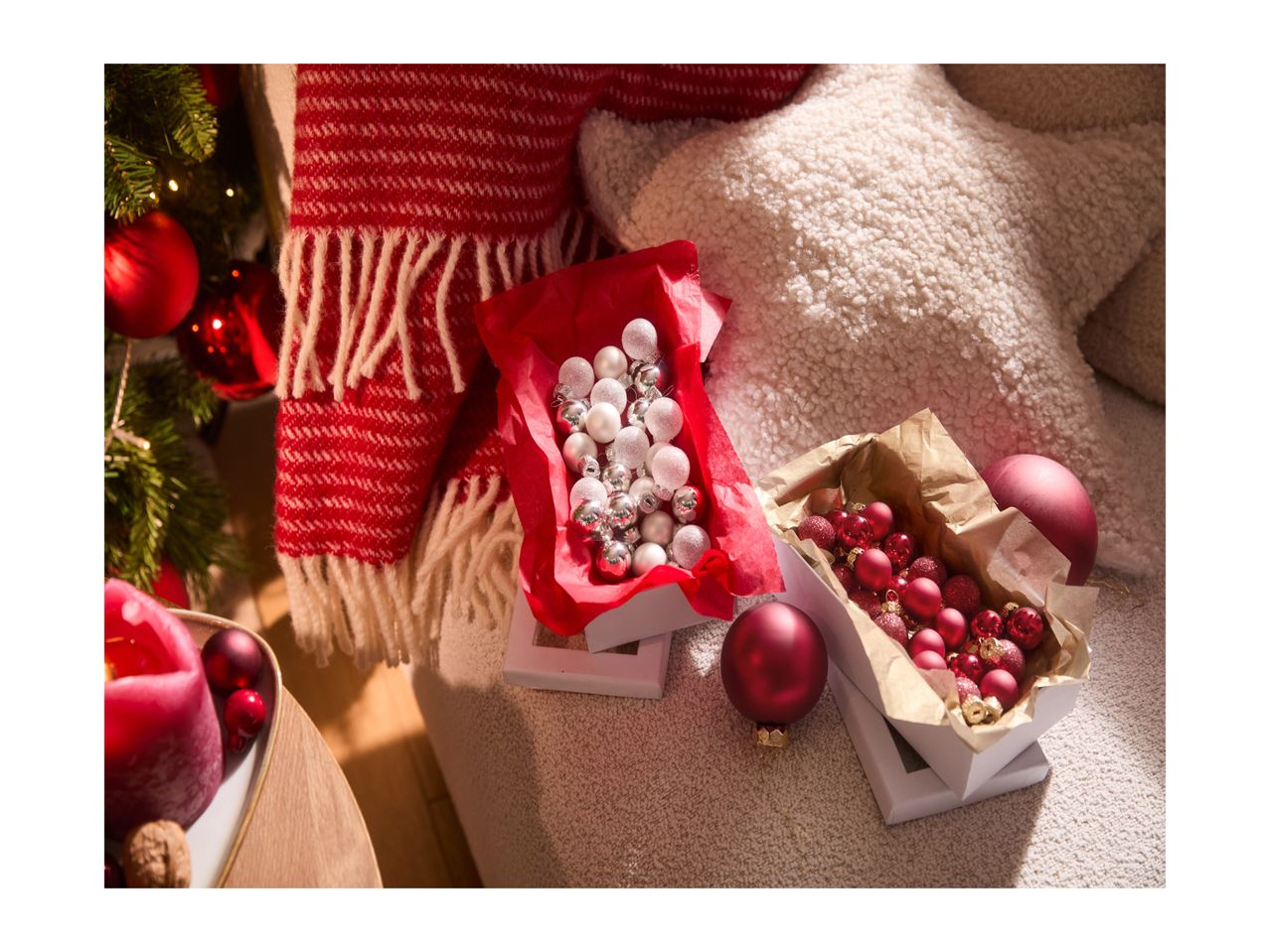 Christmas decorations: two boxes of baubles, a red candle, and a festive blanket.