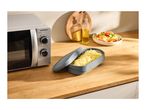 Microwave oven, pasta cooker, and a bowl of pasta salad on a wooden kitchen counter.