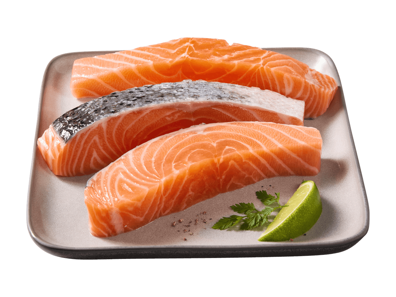 Tre filetti di salmone fresco su un piatto, guarniti con prezzemolo e uno spicchio di lime.