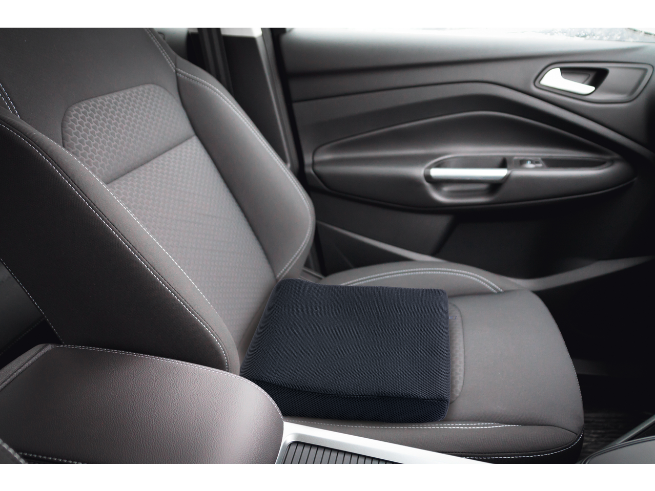ULTIMATE SPEED® Seat Pad/Cushion in a car seat, black with white stitching