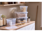 W5 Storage Box with Lid, clear plastic, stacked on a wooden counter with bath items.