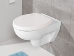White wall-mounted toilet with a closed lid in a modern bathroom with gray tiles.