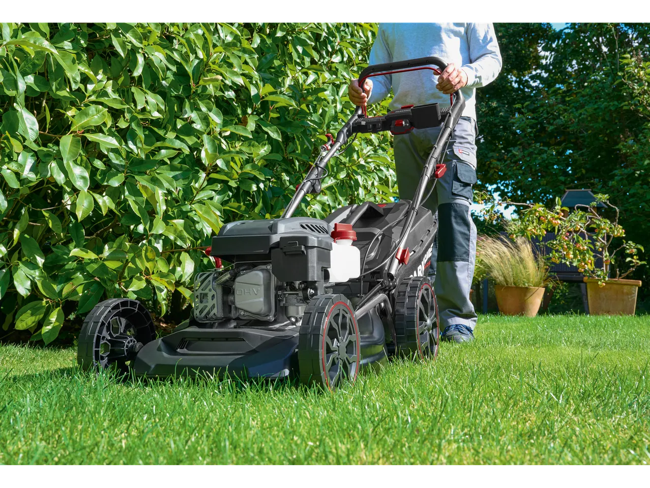 Man mowing lawn with a Parkside Performance® petrol lawnmower in a garden.