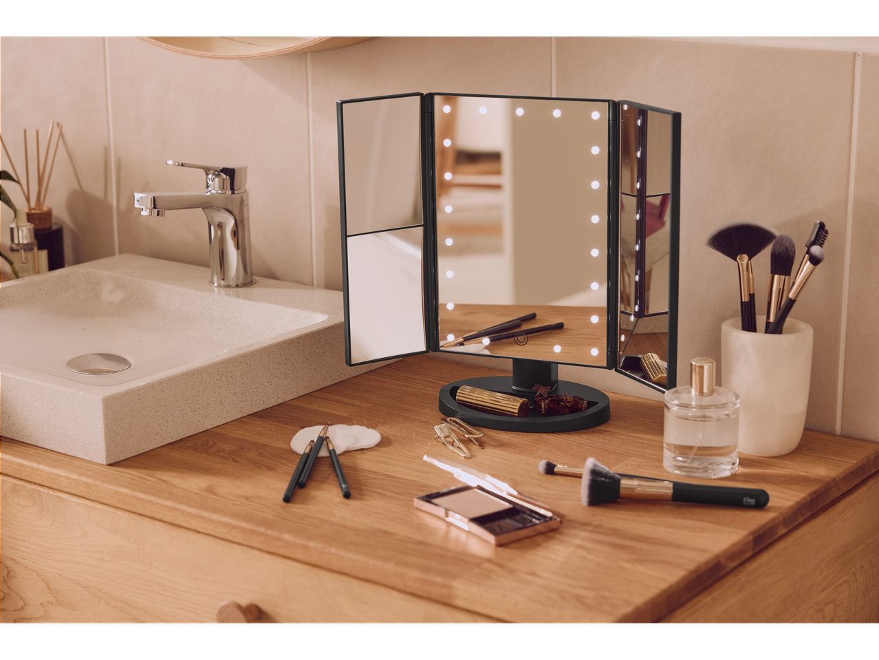 Cien BEAUTY LED makiažo veidrodis ant medinio tualetinio staliuko su kosmetika ir kriaukle.