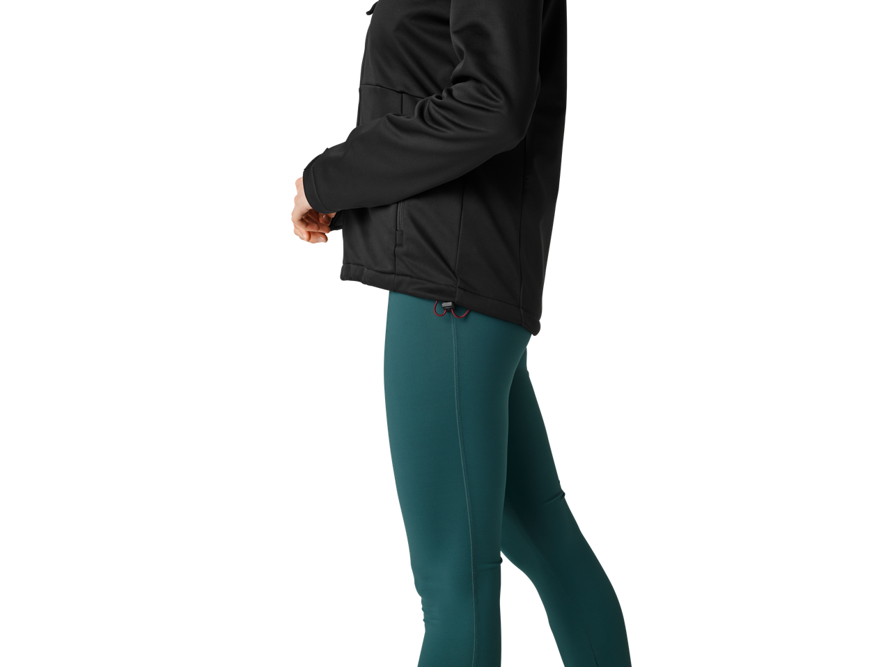 En kvinna i en svart softshelljacka och mörkgröna leggings.