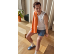 Homem de regata atlética branca e calções azuis com uma toalha laranja