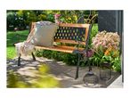 Garden bench with cushion and throw, surrounded by flowers and two decorative lanterns.
