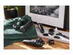 Electric shaver and hair clippers with various attachments, scissors, and oil on a wooden surface.
