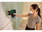 Uma mulher usando máscara e óculos de proteção usa um pulverizador de tinta Parkside para pintar uma parede.