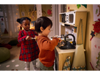 Two children playing with a Playtive Wooden Play Kitchen, one stirring a pot, the other holding a utensil.