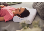 Woman sleeping on a memory foam pillow in bed, wearing a pink t-shirt.