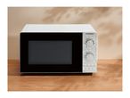 A white microwave with manual dials on a wooden surface