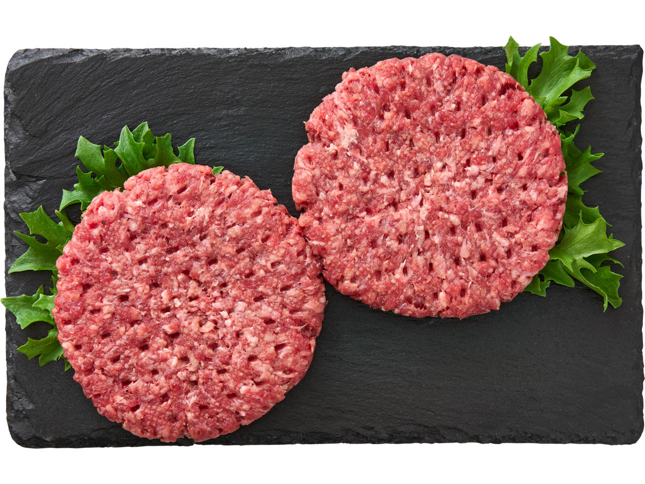 Kaks toores veiseliha burgeripätsi õrnalt kivitaolisel aluspinnal salatiga.