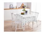 Dining table with a white tablecloth featuring a grey abstract pattern, surrounded by white chairs.