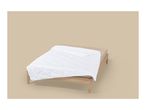 White quilted duvet on a bed with a light brown frame and sheet.
