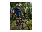 Two men mountain biking on a forest trail, wearing helmets and sportswear.