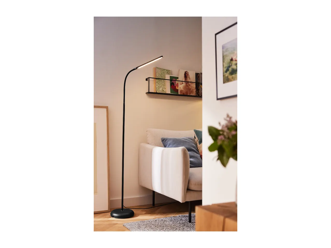 Modern black floor lamp illuminating a cozy living room with a sofa and decor.