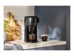 Black coffee machine on a kitchen counter, with two glasses of coffee and mint.