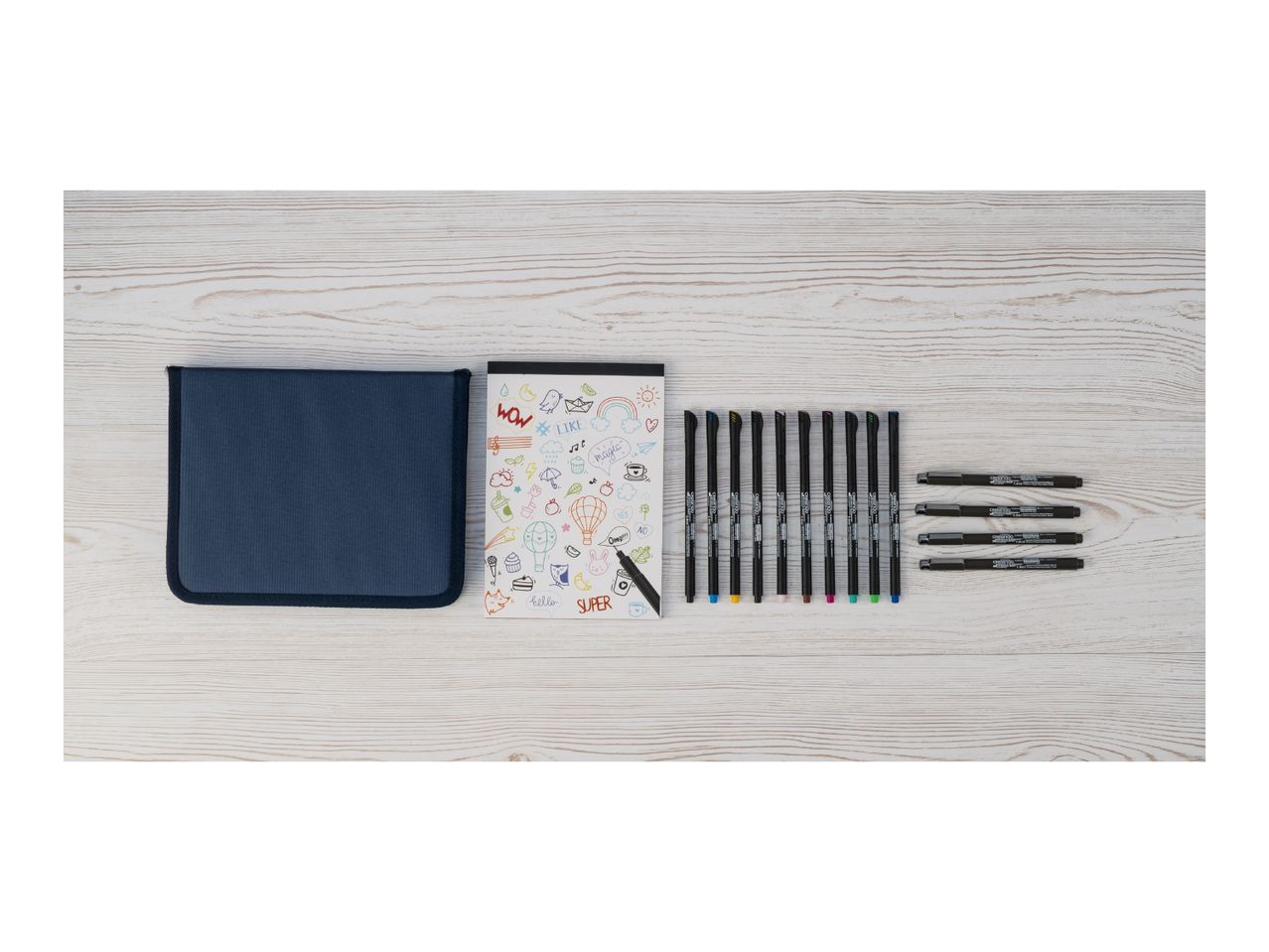 A set of colorful pens, black fineliner pens, and a sketchbook with doodles.