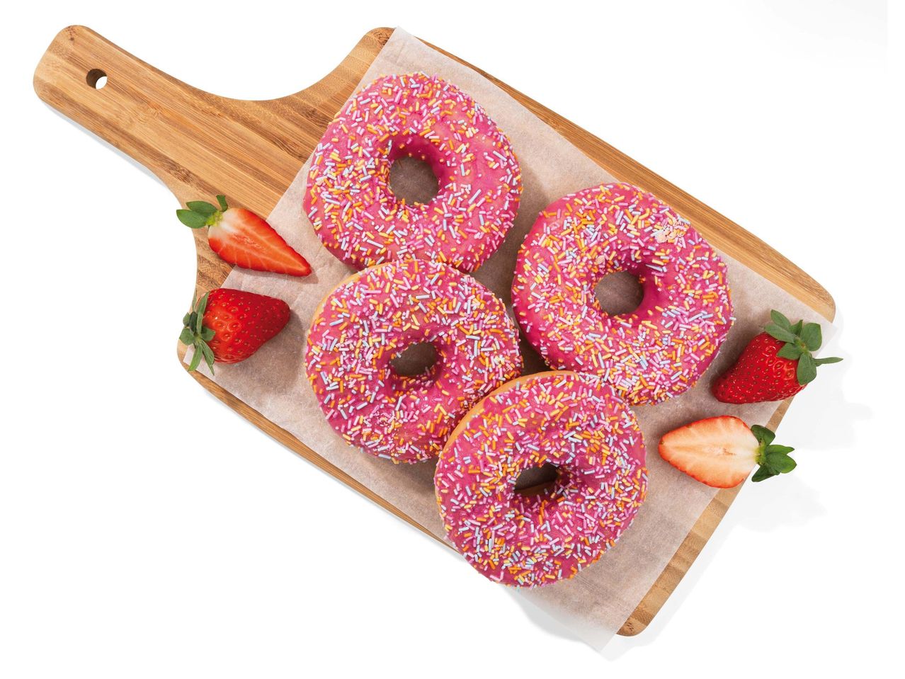 Rózsaszín, színes cukorkával szórt fánkok és eper bambusz vágódeszkán.