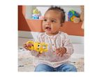 Happy baby playing with a yellow animal-shaped rattle on a patterned rug.