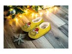 Grinch slippers on a wooden floor with Christmas tree and lights.