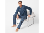 Bărbat în pijamale Esmara® Men, cu bluză albastră și pantaloni în carouri, așezat pe un scaun.