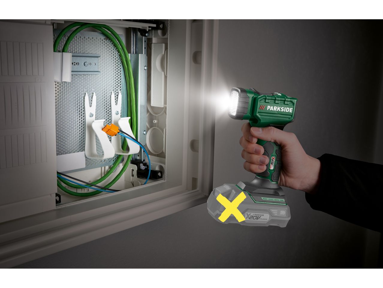 Una torcia Parkside illumina una scatola di derivazione elettrica.