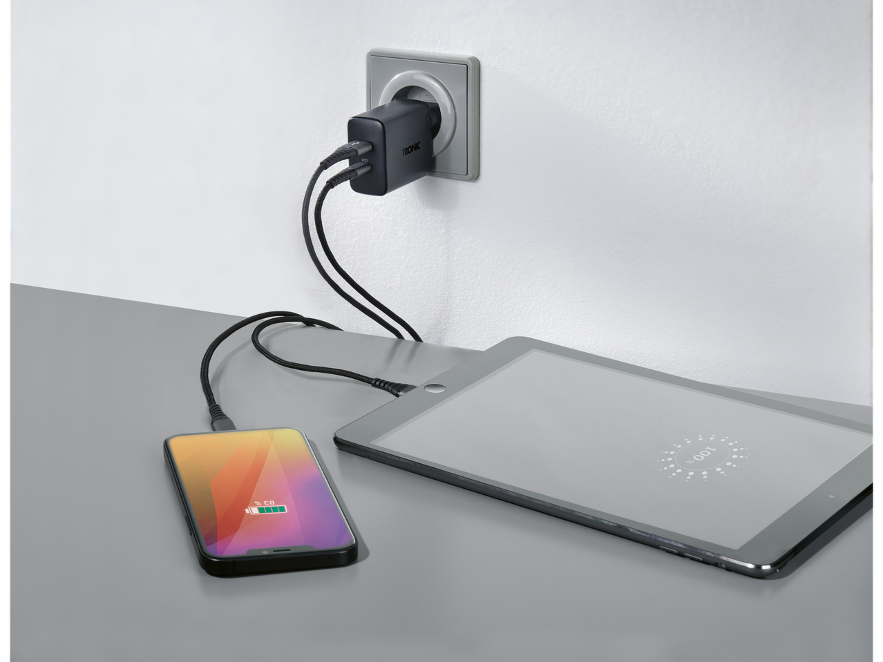 Tronic dvostruki USB punjač uključen u utičnicu, puni telefon i tablet.