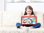 Момиче седи на диван, гледайки таблет Paw Patrol Lexibook.