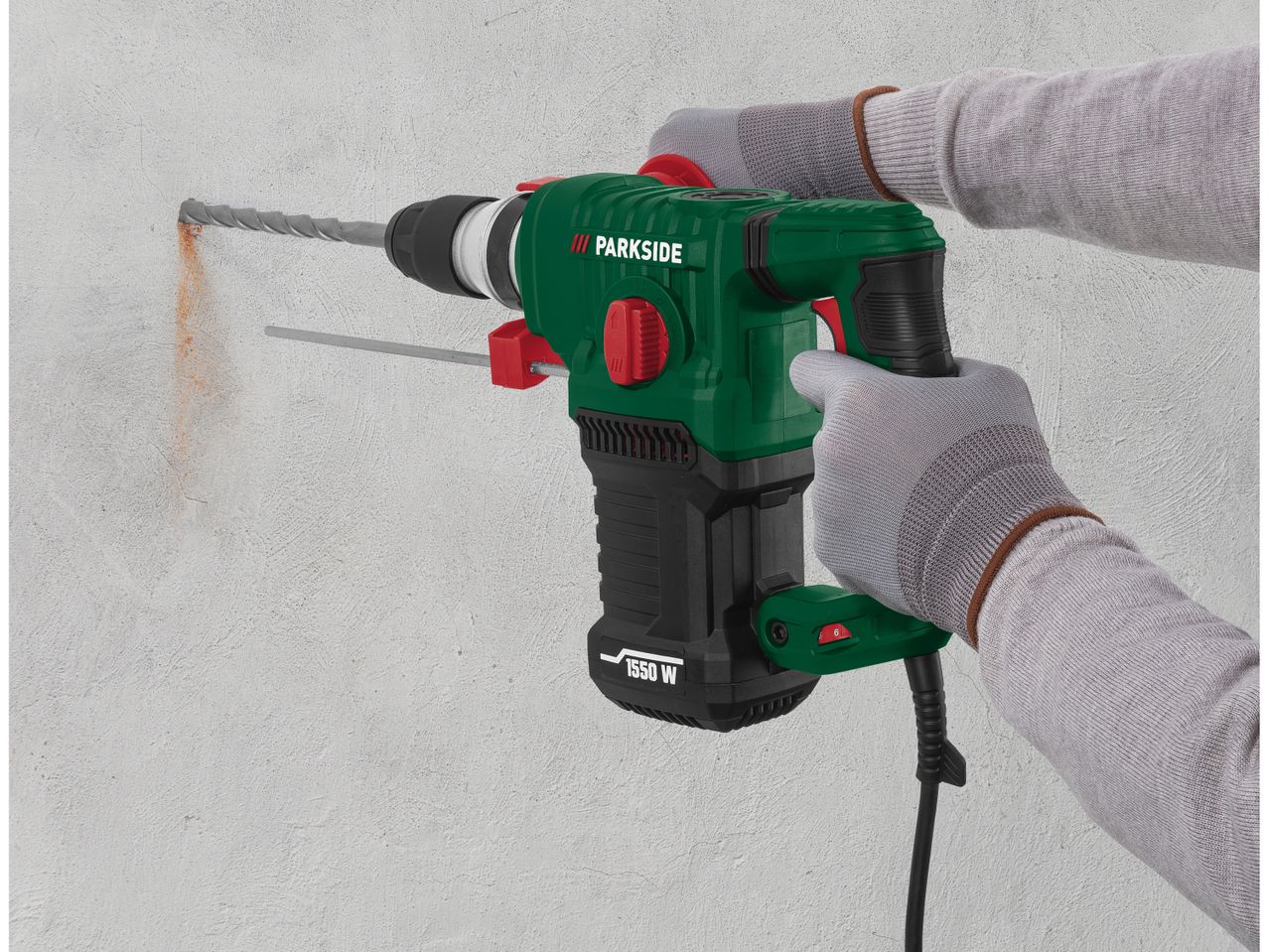A person uses a Parkside 1550 W hammer drill to make a hole in a concrete wall.
