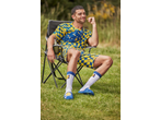 Man in yellow and blue checkered t-shirt, shorts, socks, and slides, sitting in a camping chair.