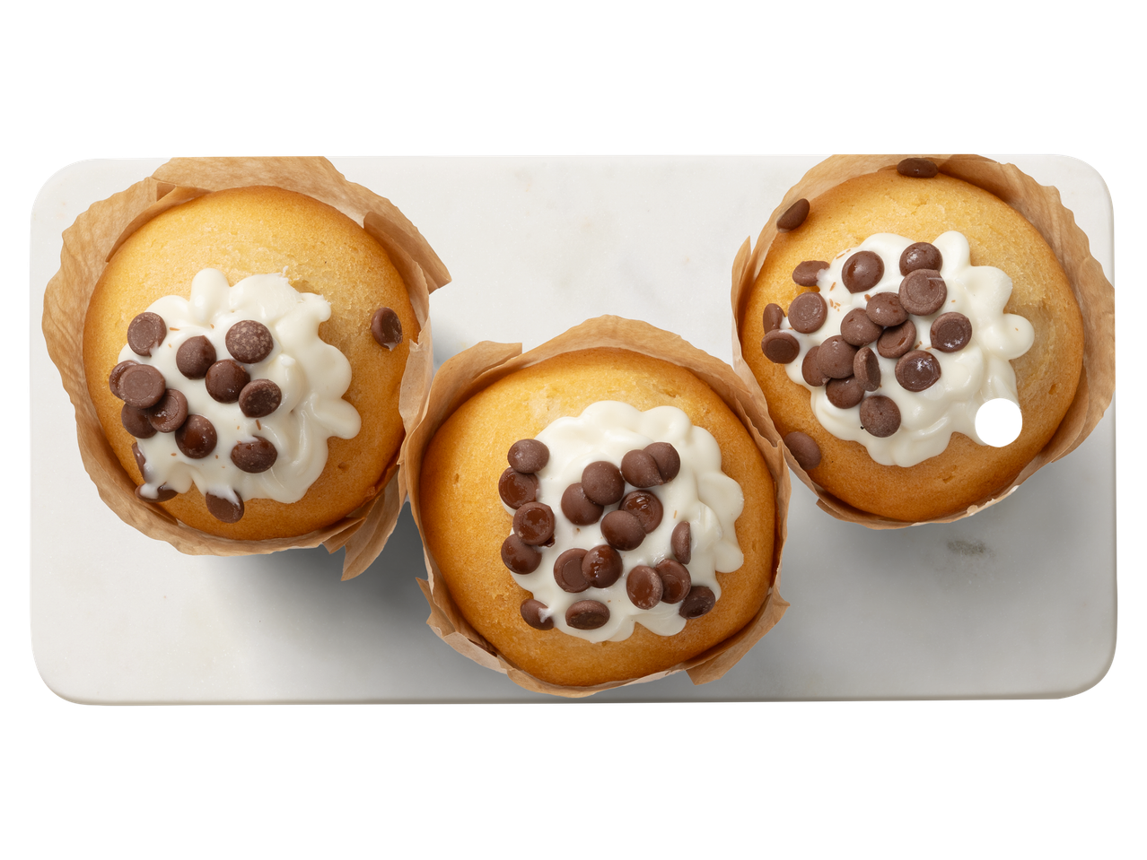 Három vaníliás muffin fehér cukormázzal és csokoládédarabokkal egy fehér tálcán.