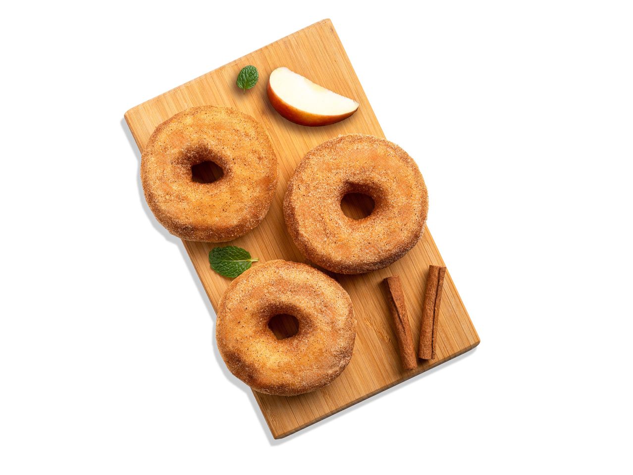 Fahéjas fánk almával, fahéjrúddal és mentával egy fa vágódeszkán.